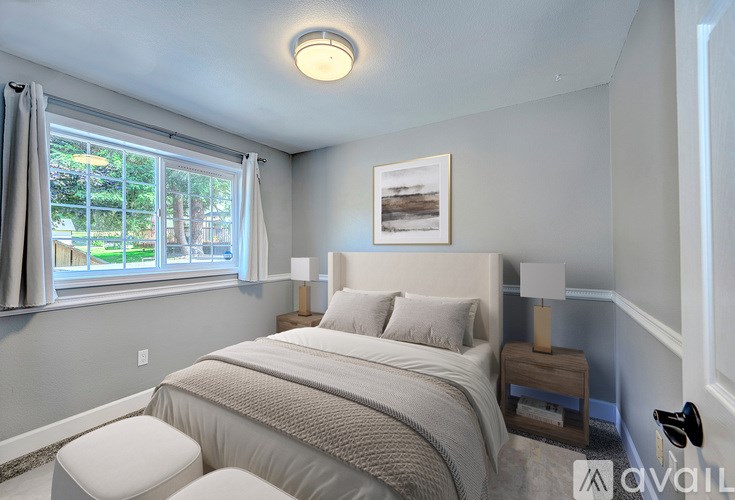A bedroom with a large bed and a window with curtains.