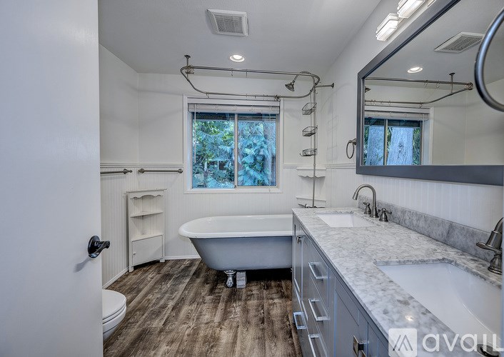 A bathroom with a tub, sink, and mirror.