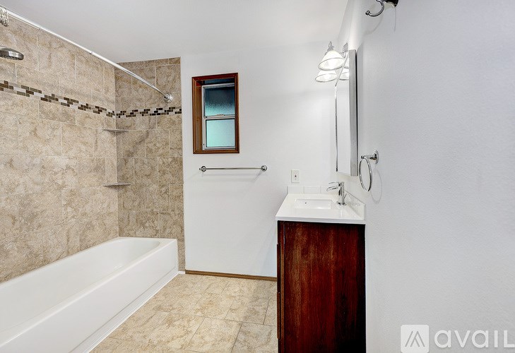 A bathroom with a tub, sink, and mirror.