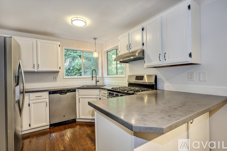 A kitchen with white cabinets and a stainless steel refrigerator.