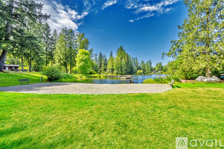 A park with a pond, trees, and a bench.
