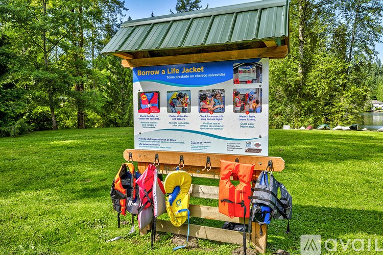 A sign for a life jacket loaner program sits on a bench in a park.