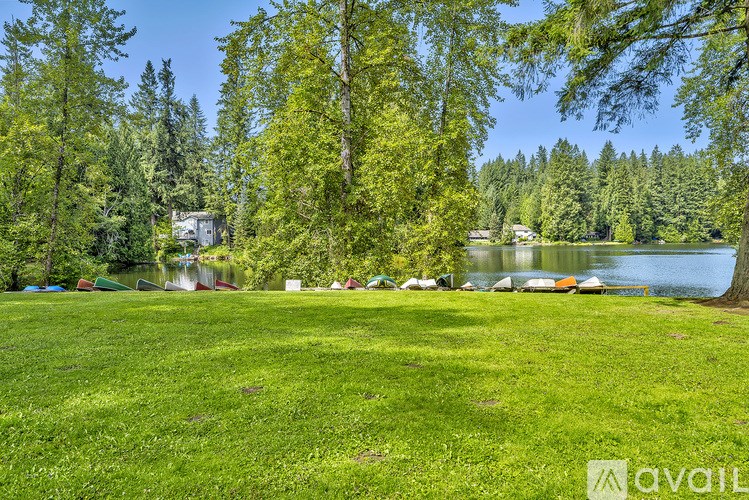 A grassy field with trees and a lake in the background.
