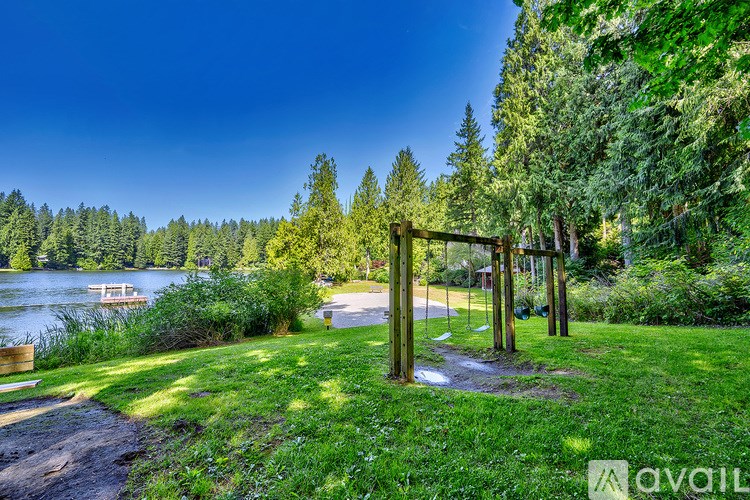A serene park with a lake, trees, and a wooden archway.