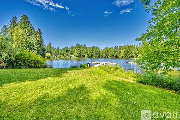 A serene landscape with a lake, trees, and a clear sky.