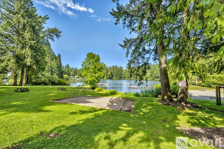A playground with a swing set is located in a grassy area near a lake.