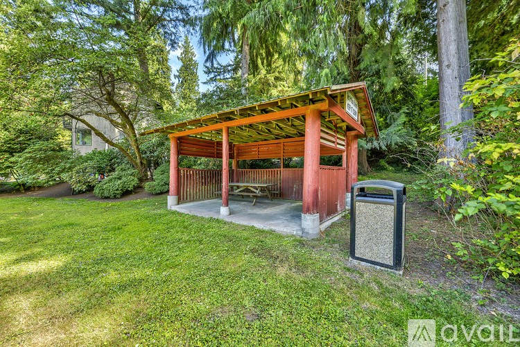 A small red pavilion with a black trash can in front of it.