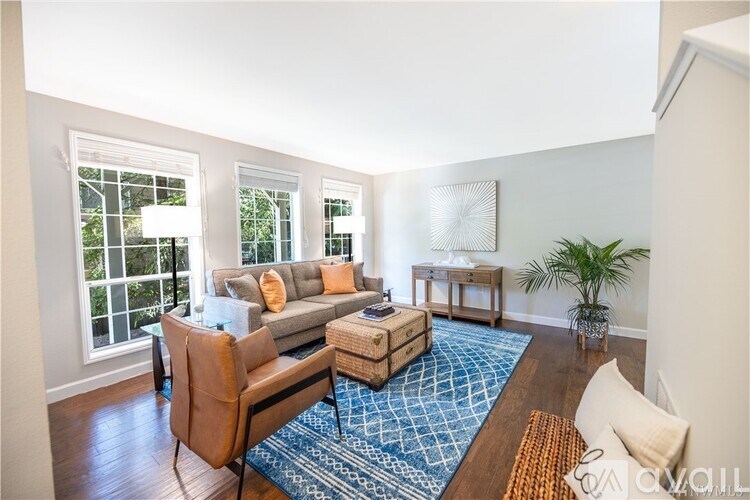 A living room with a couch, chairs, and a rug.