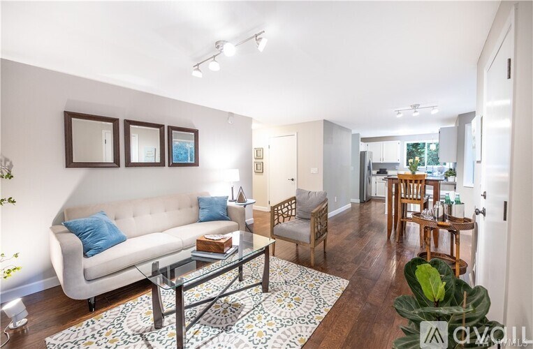 A living room with a white couch and a glass coffee table.