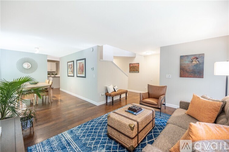A living room with a blue rug and a brown ottoman.