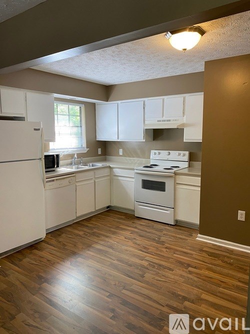 A kitchen with white appliances and wooden floors.