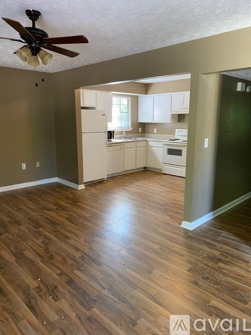 A kitchen with a fan on the ceiling and wooden flooring.