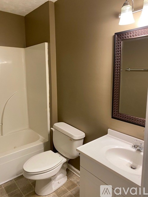 A white toilet sits next to a bathtub in a bathroom.