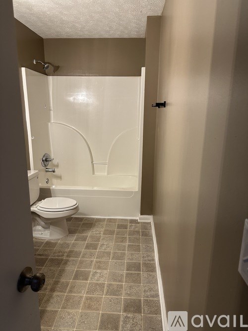 A bathroom with a toilet, tub, and tiled floor.