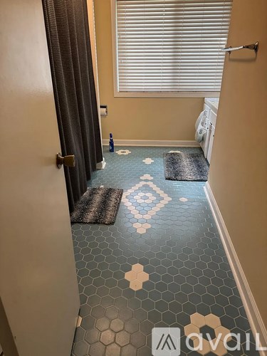 A hallway with a blue tiled floor and a rug with a hexagonal pattern.