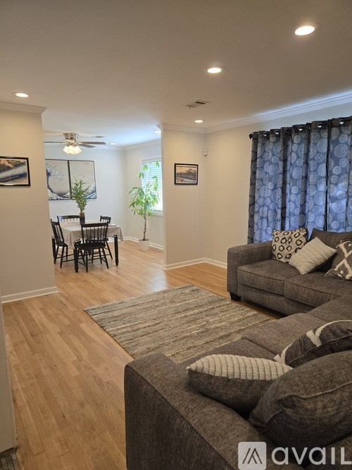 A living room with a grey couch and a dining table with chairs.