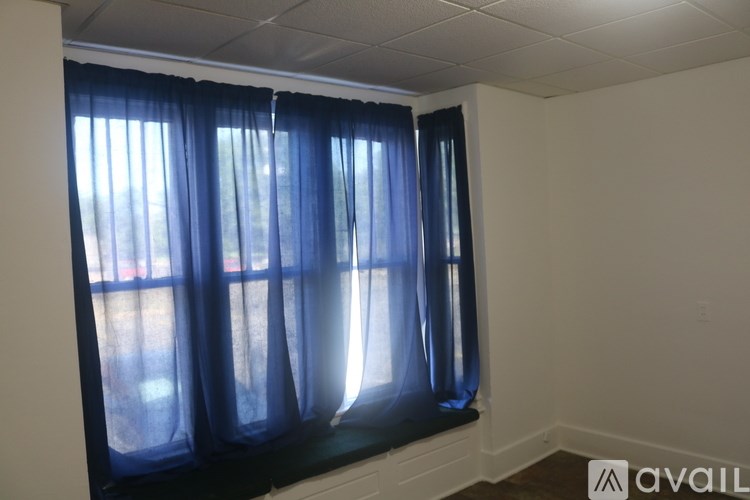 A room with a window covered by blue curtains.