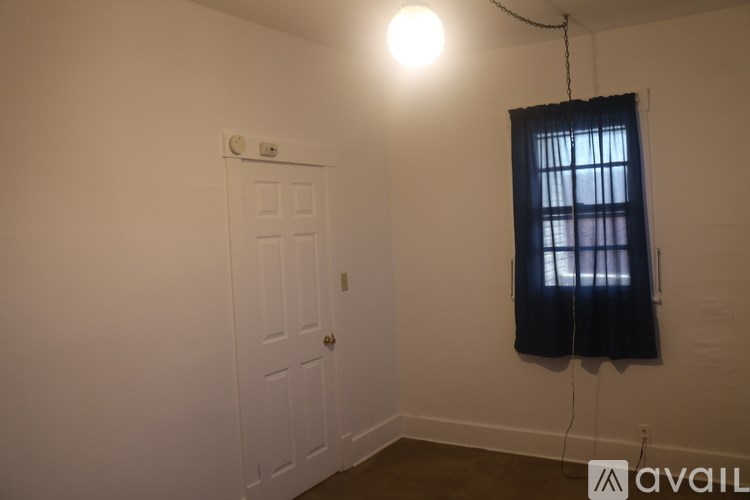 A room with a white door and a window with black curtains.