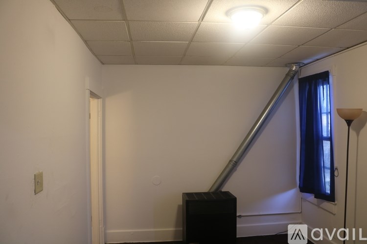 A room with a white ceiling, a black speaker, and a window with blue curtains.