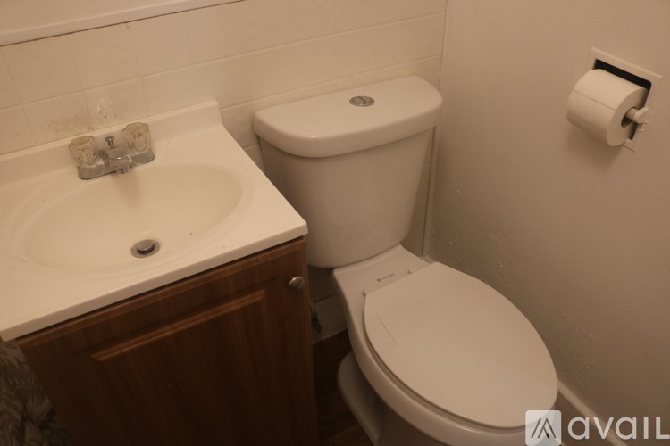 A white toilet sits next to a white sink in a bathroom.