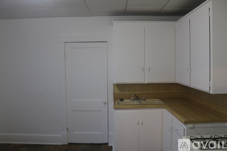 A kitchen with white cabinets and a wooden counter top.