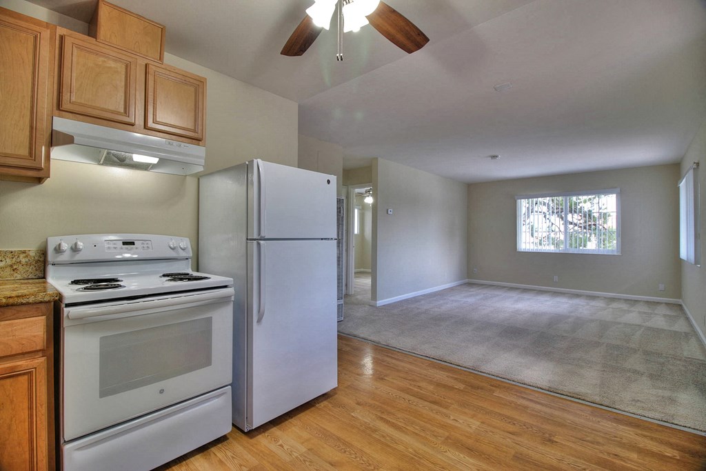 A kitchen with a stove, refrigerator, and wooden cabinets.