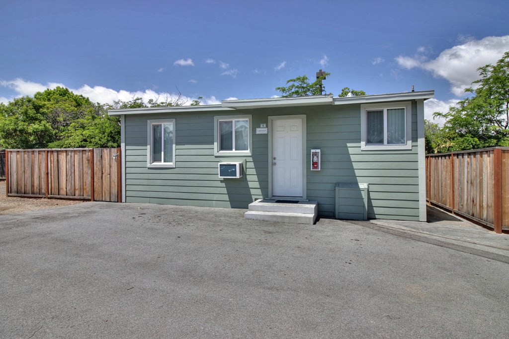 A small green house with a white door and windows.