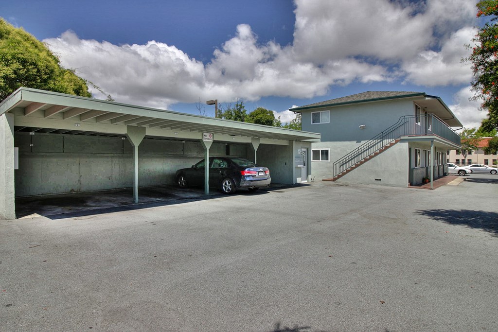 A car is parked in a garage under a covered area.
