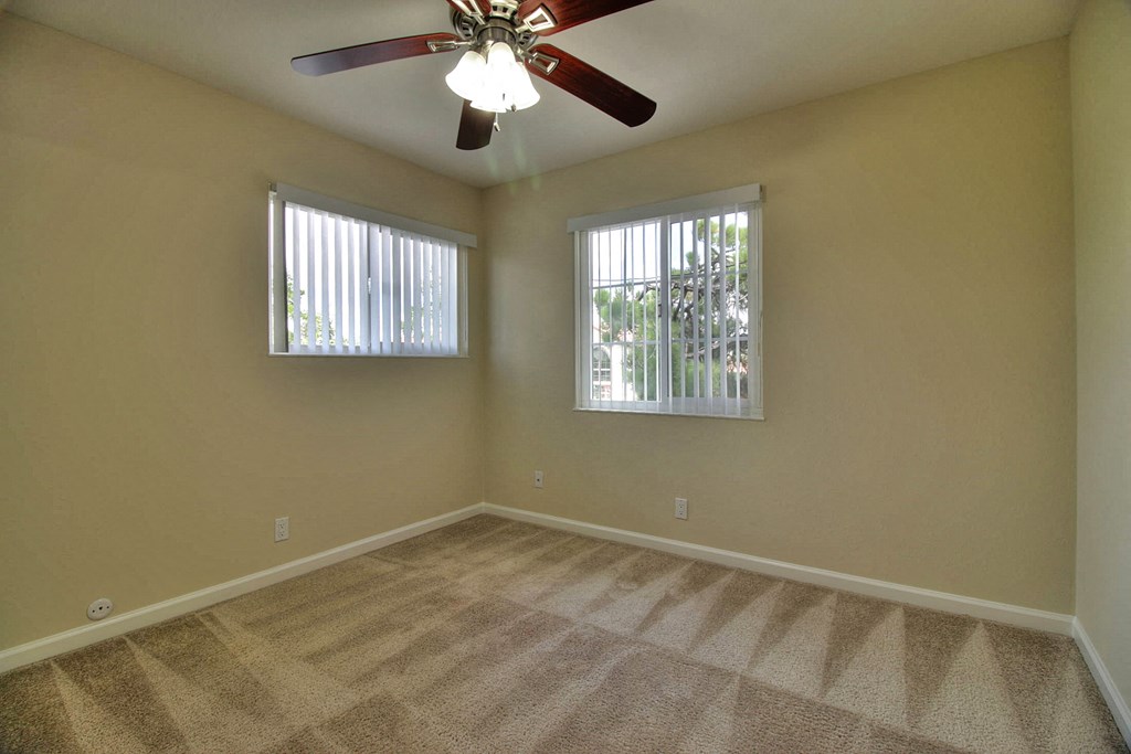 A room with a ceiling fan and carpeted floor.
