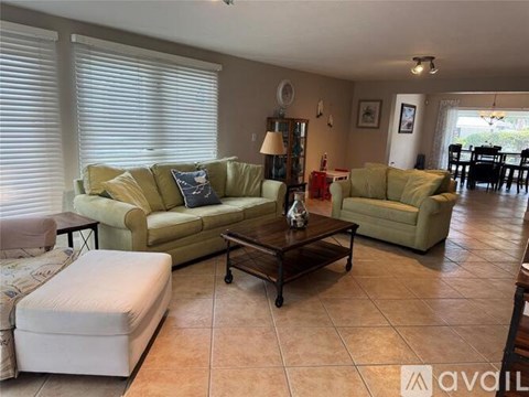A living room with a green couch and a white ottoman.