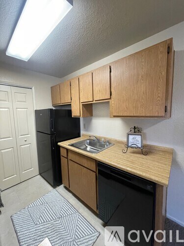 A kitchen with wooden cabinets and a black refrigerator.