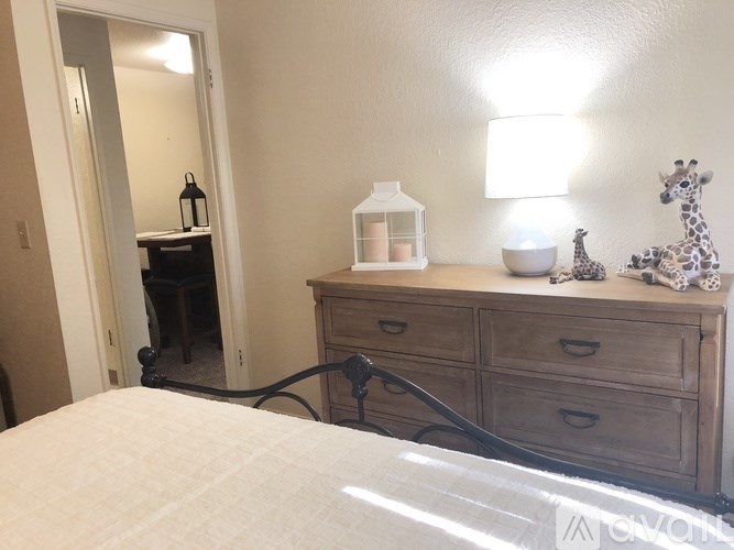 A bedroom with a bed, dresser, and a lamp.