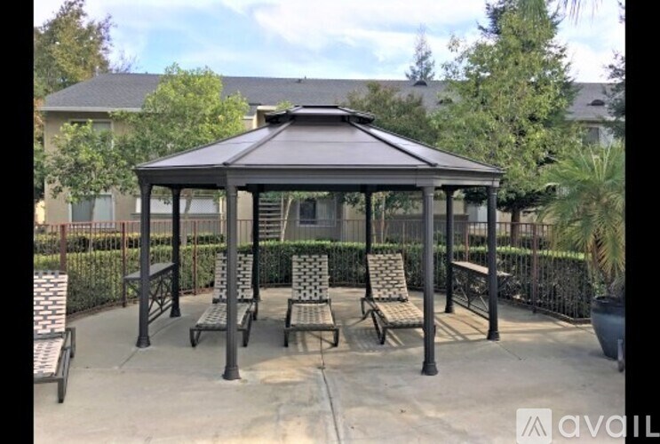 A gazebo with four chairs and a table is surrounded by a fence.