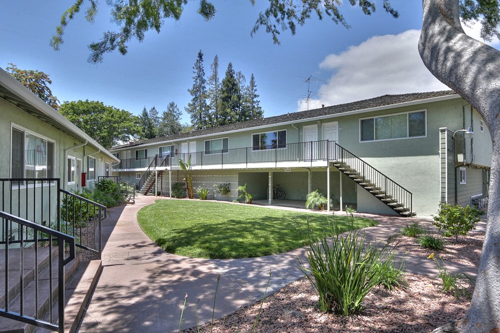 A sunny day at the apartment complex with green grass and trees.