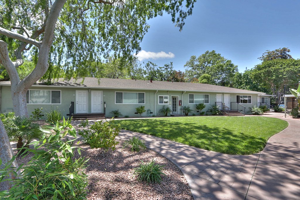 A building with a green lawn and trees in front.