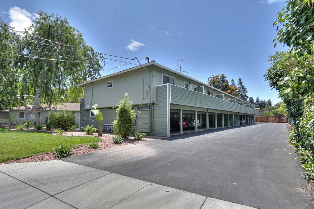A building with a grey facade and a parking lot in front.