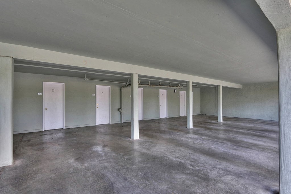 A large empty room with concrete floors and white pillars.