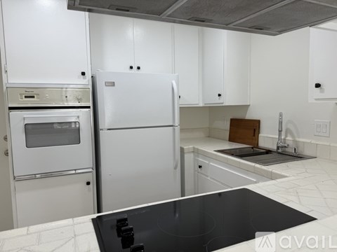 A kitchen with white cabinets and a black countertop.