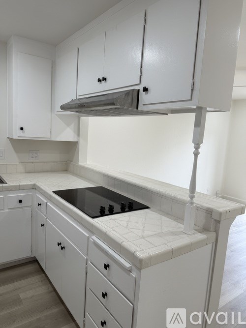 A kitchen with white cabinets and a black countertop.