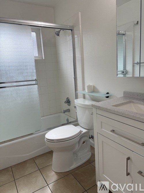 A white toilet in a bathroom with a white sink and a white bathtub.