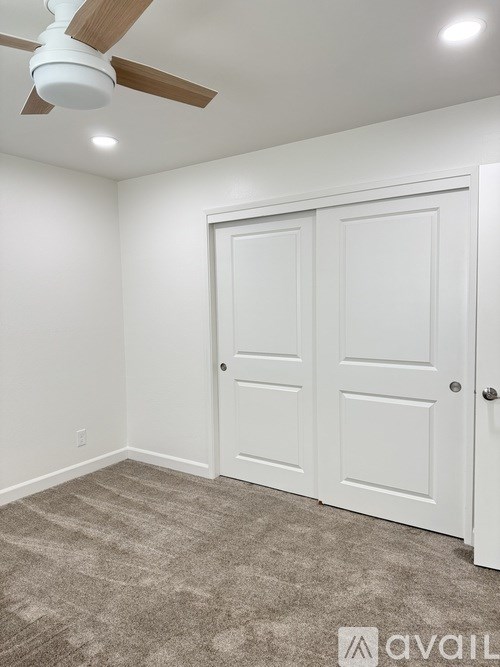 A room with a ceiling fan and two doors.