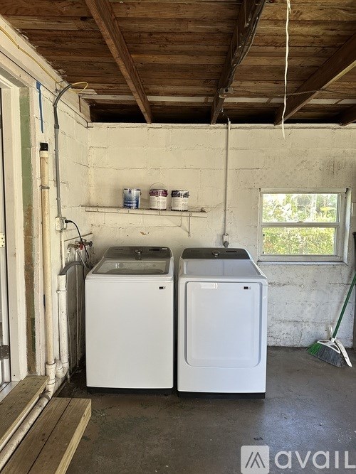 A room with two washing machines and a window.
