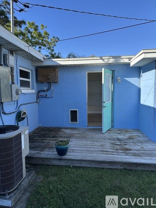 A blue house with a wooden deck and a green plant.