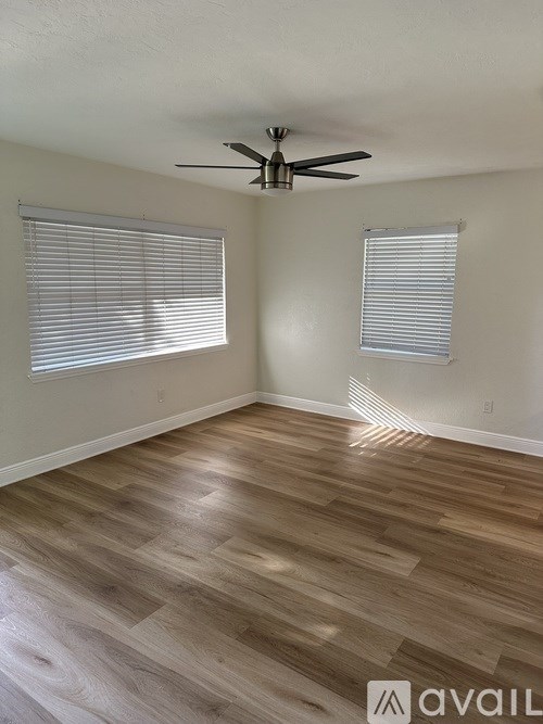 A room with a ceiling fan and wood flooring.