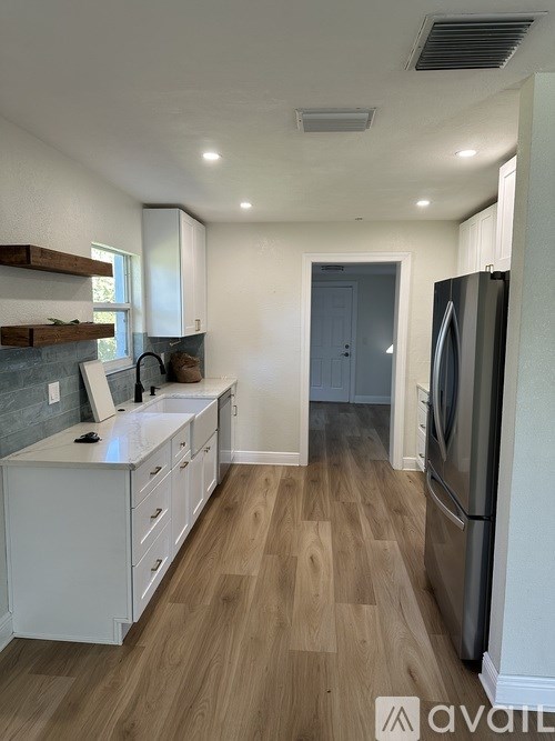 A kitchen with a refrigerator, countertop, and wooden floors.