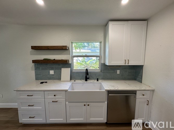 A kitchen with white cabinets and a marble countertop.