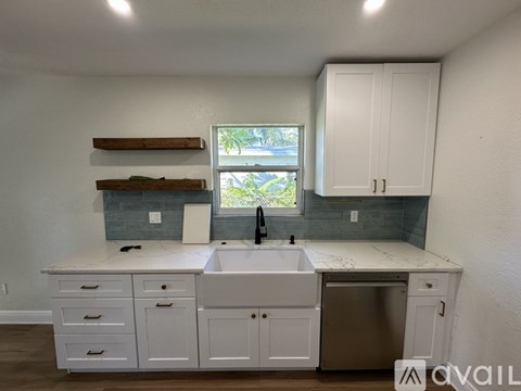 A kitchen with white cabinets and a marble countertop.