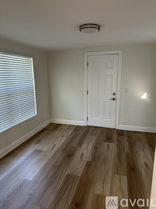 A room with a white door and wooden flooring.