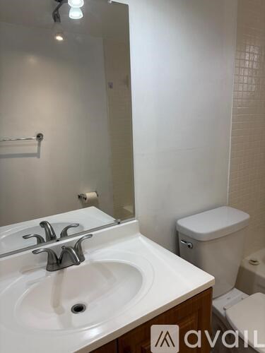 A bathroom with a sink, toilet, and mirror.
