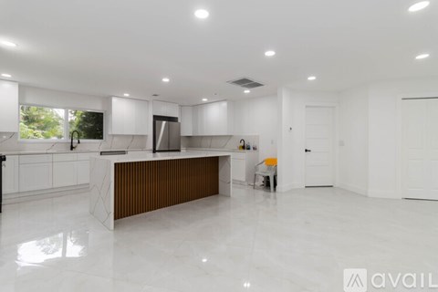 A modern kitchen with white cabinets and a wooden island.